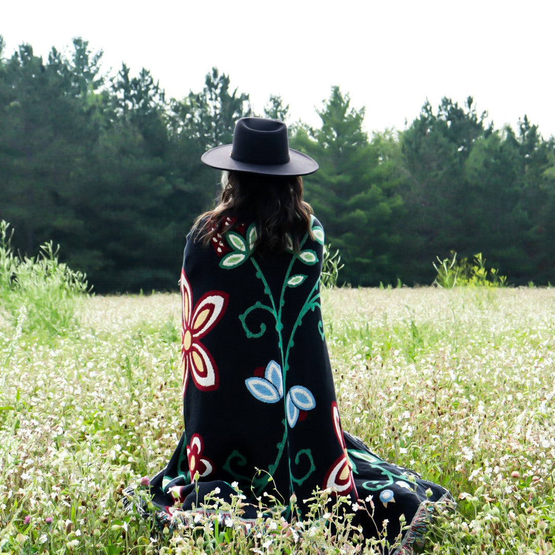 Dark variant of Woodland Floral Throw wrapped around a woman.