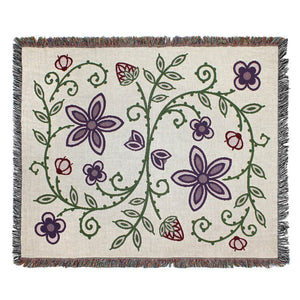 Product photo of Woodlands throw blanket in light cream color, design shows- strawberries, wild rice, blueberries, and a green vine connecting all the plants